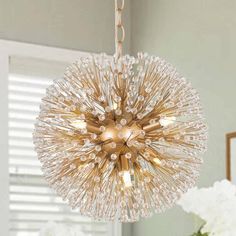 a chandelier hanging from a ceiling in a room with white flowers on the table