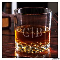 a shot glass sitting on top of a wooden table next to a book and glasses