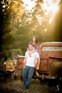 a man and woman sitting on the back of an old truck