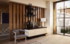 a living room filled with furniture next to a tall wooden wall covered in plants and potted plants