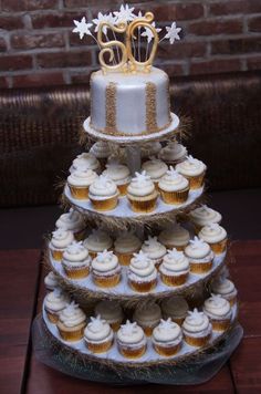 a three tiered cake with cupcakes on the bottom and gold decorations on top