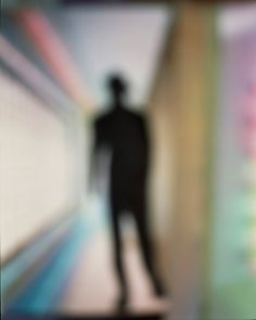 a blurry image of a man standing in front of a wall with an abstract background