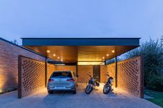 two motorcycles are parked in front of a car garage with lights on the side of it