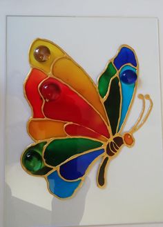 a stained glass butterfly sitting on top of a white wall