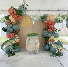 a table topped with balloons and fake animals next to a wine barrel filled with grapes