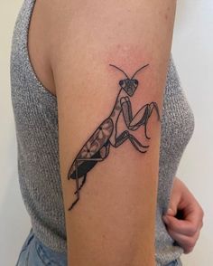 a woman's arm with a tattoo of a praying mantissa