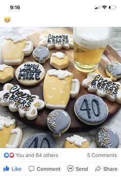 a wooden platter filled with lots of decorated cookies next to a glass of beer