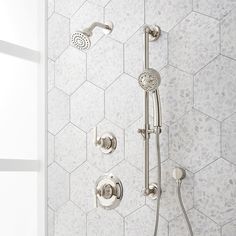 the shower head and handset are shown in this bathroom setting with hexagonal tiles