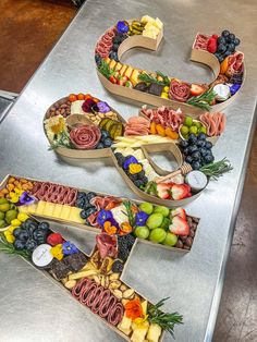 two letters made out of fruits and vegetables on a metal counter top with the letter e spelled out