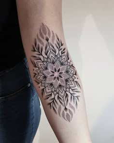 a woman's arm with a black and white tattoo design on the left forearm