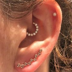 a close up of a person wearing an ear piercing with diamonds on the inside of it