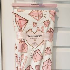 a pink and white towel hanging from a hook on a door with the name juicy couture printed on it