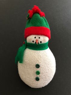 a knitted snowman ornament on a black surface