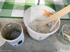 two buckets filled with paint next to some chopsticks