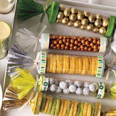 an assortment of desserts and snacks on a white tray with green decorations around them