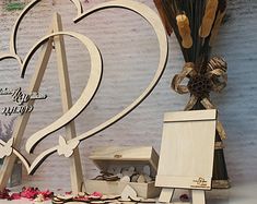 a heart shaped wooden sign sitting on top of a table next to a vase filled with flowers