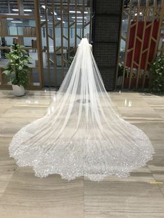 a white wedding veil with sequins hanging from the side on a marble floor