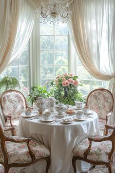 a dining room table is set with tea cups and saucers, plates and flowers