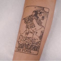 a tattoo on the arm of a person with a tarot card in front of them