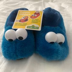 the sesame street slippers are blue with googly eyes and noseballs on them