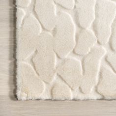 a white area rug with hearts on the top and bottom, in front of a wooden floor