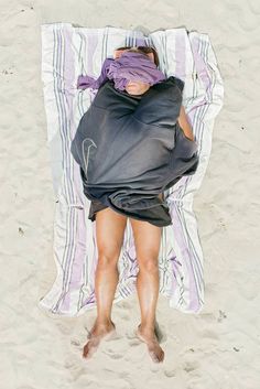 a person laying on top of a towel in the sand