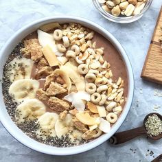 a bowl filled with cereal and nuts on top of a table next to a cutting board