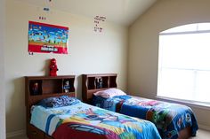 two twin beds in a bedroom with posters on the wall above them and an open bookcase