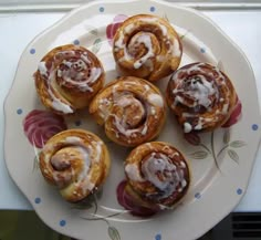 several cinnamon rolls with icing on a plate