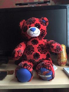 a red and black teddy bear sitting on top of a desk