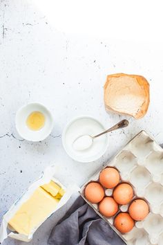 eggs, butter and other ingredients on a white counter top with an egg carton