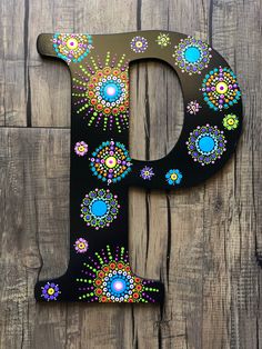 the letter p is decorated with colorful flowers and daisies on a wood background,