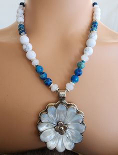 Beautiful hand carved mother of pearl necklace.  It features a rare find 2 inch diameter hand carved mother of pearl daisy flower pendant, moonstone, blue sea sediment, howlite and silver plate and hematite beads. It includes sterling silver chain and lobster clasp with a 3 inch extender chain. Necklace is adjustable from 19 inches to 22 inches. Gift Box Included. Handmade Silver Flower-shaped Beaded Necklaces, White Flower-shaped Beaded Necklace, Adjustable Flower-shaped Beaded Necklace With Large Beads, White Flower-shaped Mother Of Pearl Necklace, Luxury Flower-shaped Mother Of Pearl Jewelry, Mother Of Pearl Necklace, Ruby Necklace, Labradorite Necklaces, Hematite Beads