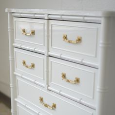 a white dresser with gold handles and drawers