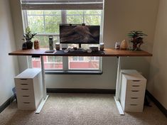 an office desk with two drawers and a computer monitor on top of it in front of a window