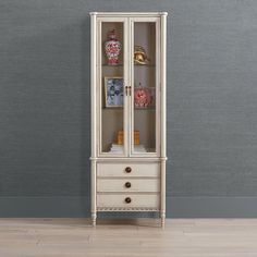 a tall white cabinet with glass doors and drawers