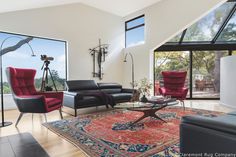 a living room filled with lots of furniture next to large windows and a painting on the wall