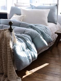 an unmade bed with blue comforter and pillows