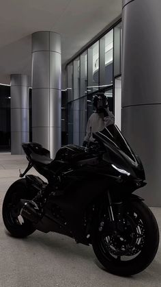 a man sitting on top of a motorcycle in front of a tall building with columns