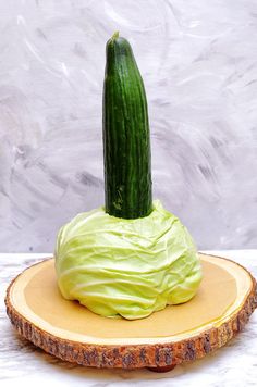 a cucumber sitting on top of a piece of wood with green frosting