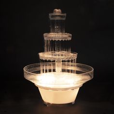 a three tiered cake stand with frosting on top and lit candles in the middle