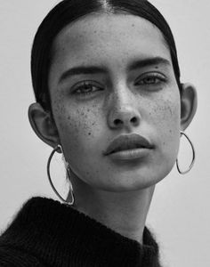 a woman with freckles on her face looking at the camera while wearing large hoop earrings