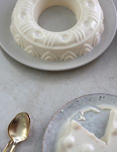 a white cake sitting on top of a table next to a plate with a piece of cake