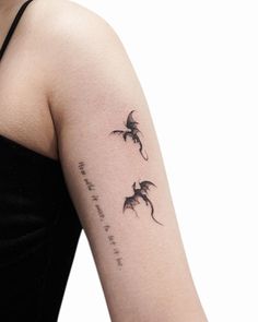 a woman's arm with two dragon tattoos on the left side of her arm