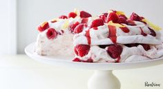 a white cake topped with whipped cream and raspberries on top of a plate