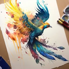 a bird painted with watercolors sitting on top of a table next to paintbrushes