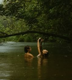 two people are in the water and one is reaching up