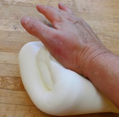 a person's hand on top of an uncooked piece of white dough