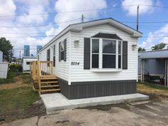 a white mobile home with black shutters on the front and stairs leading up to it