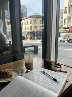 an open book sitting on top of a wooden table next to a cup of coffee